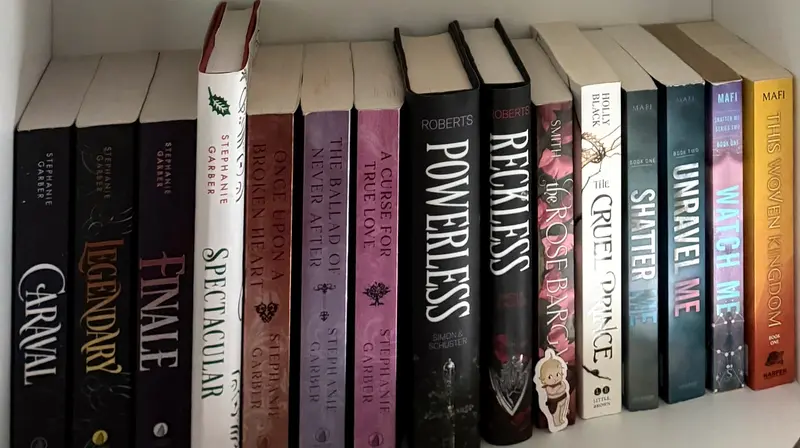 Une rangée de quinze livres sur une étagère blanche, de Caraval à This Woven Kingdom.